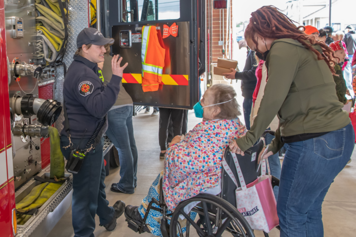 woman in wheelchair talking to firefighter at fire department opening