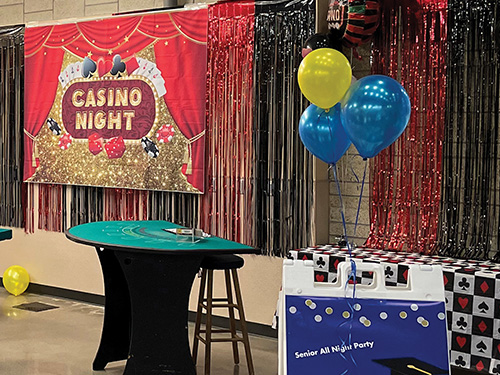 A red and gold banner that reads, "Casino Night" on the wall behind a blackjack table.