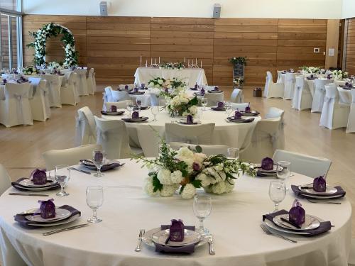 Round tables decorated in white and purple for a formal event in a ballroom.