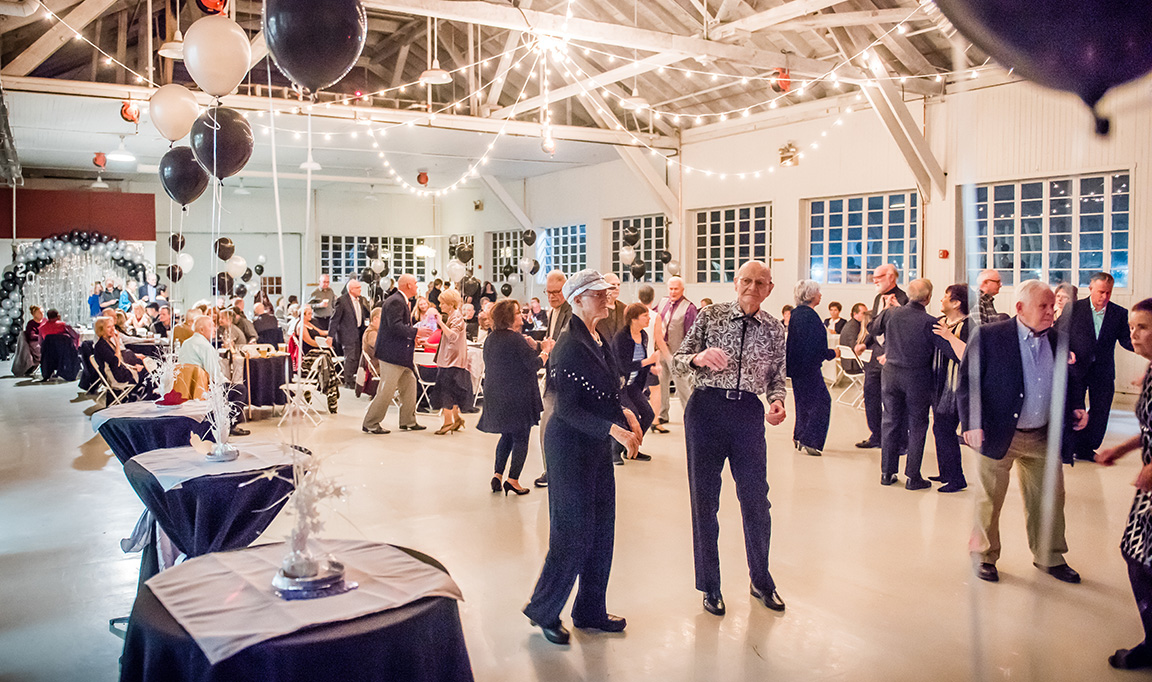 A group of seniors dancing and having fun in a decorated ballroom.