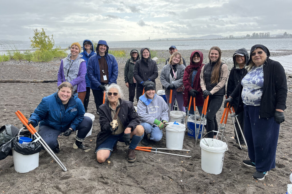 Volunteers smile at a beach litter clean up event