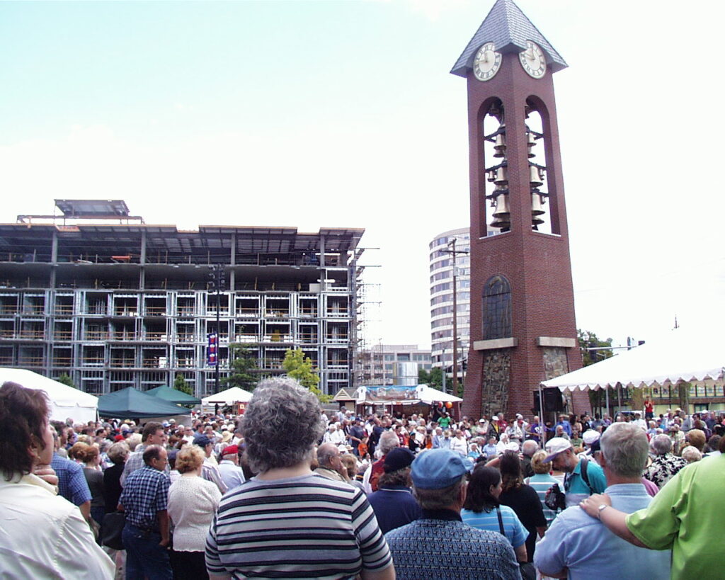 A large group of people look up at the newly constructed Salmon Run Bell Tower and Glockenspiel in 2002. 