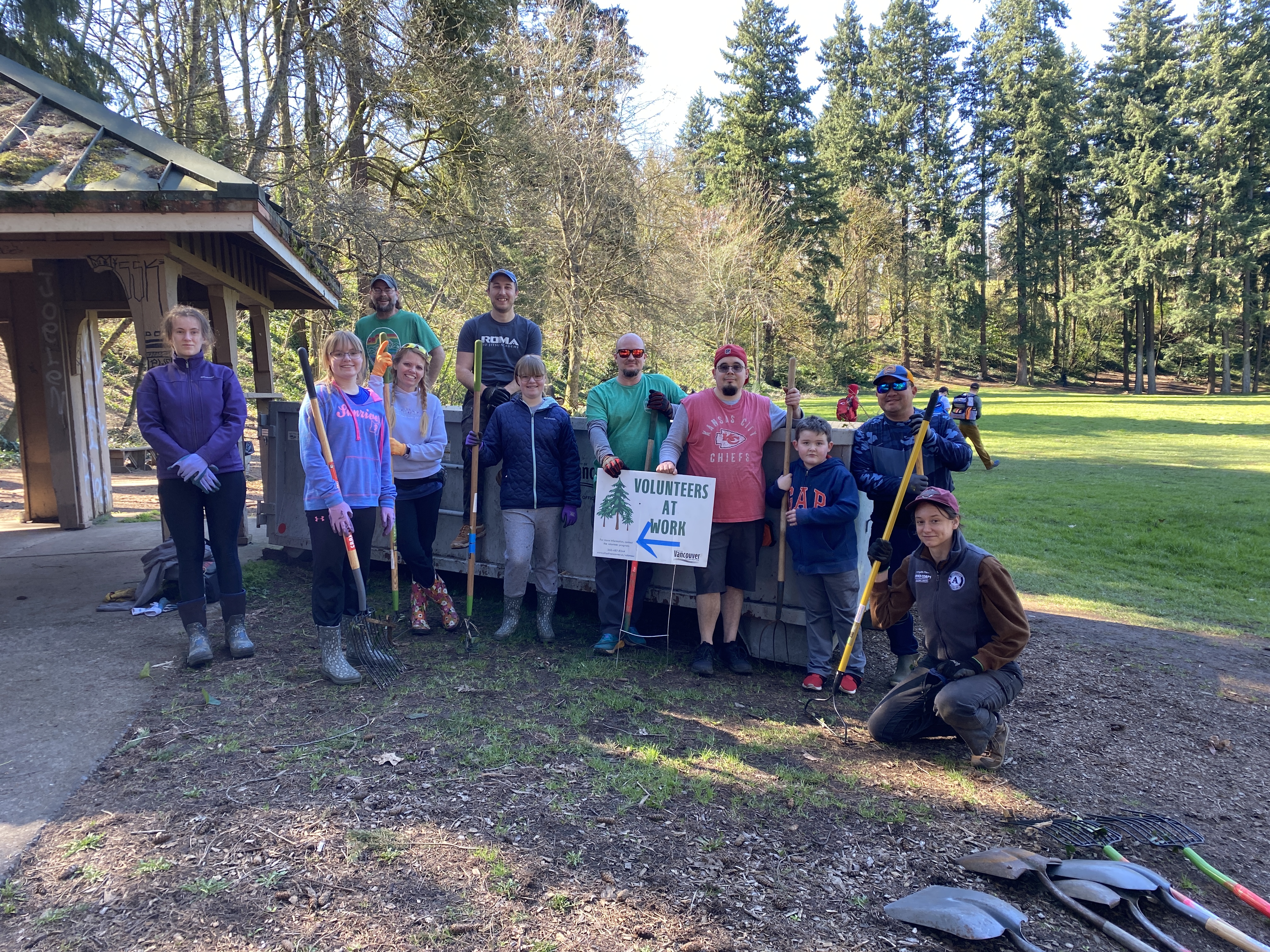 group of volunteers pose with tools outside at a park