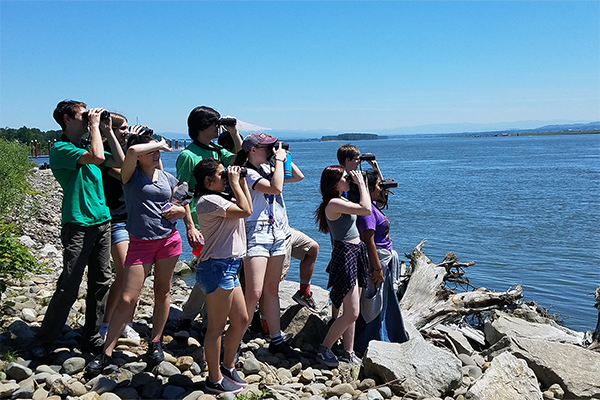 10 students looking at the Columbia River with binoculars