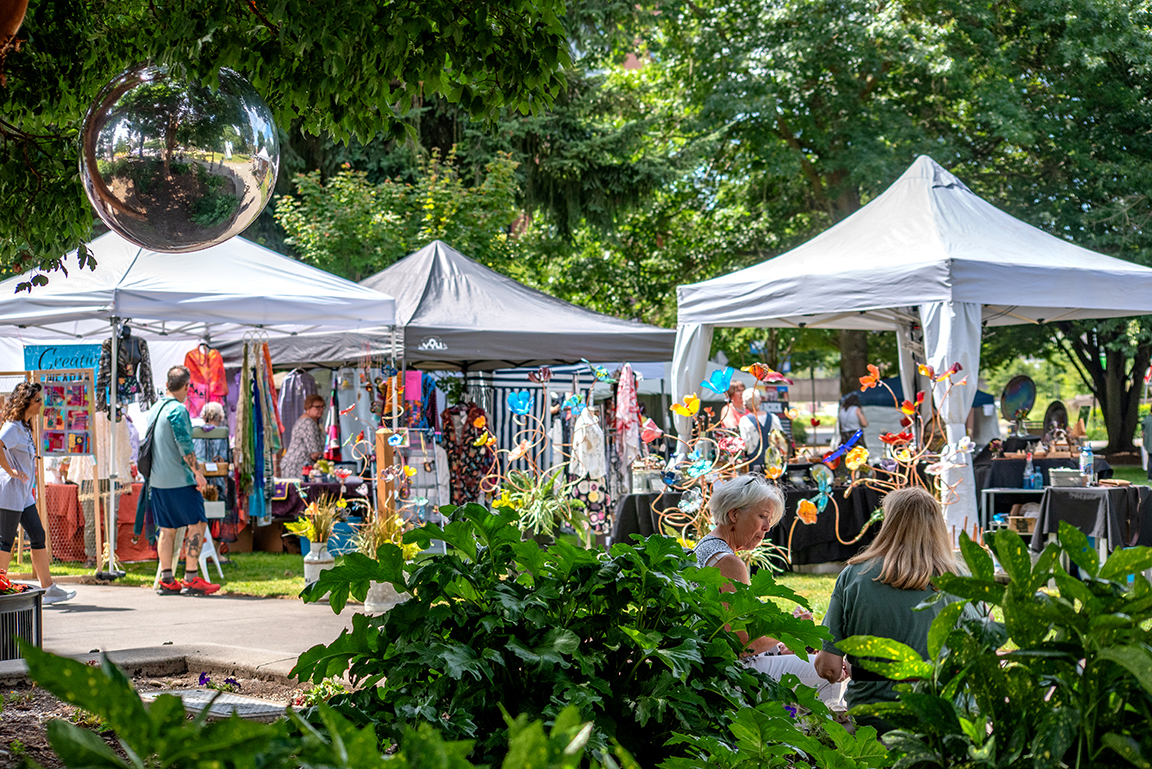 White vendor tents filled with colorful art in Esther Short Park.