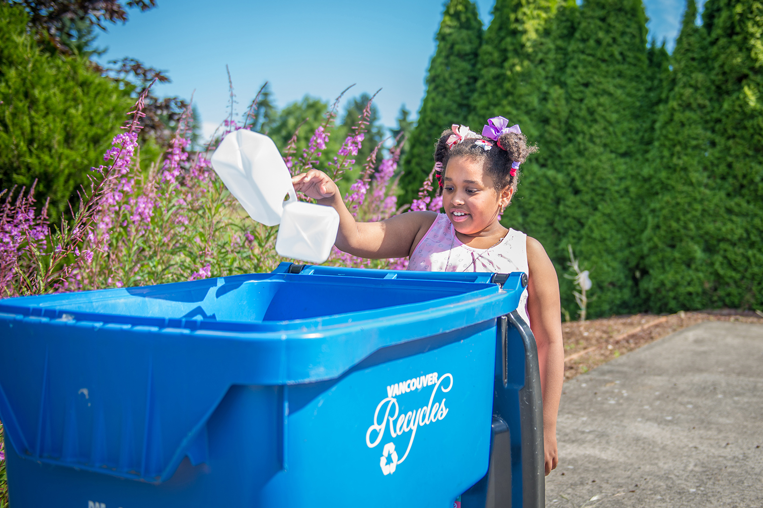 Young girl places recycling into a curbside recycling bin