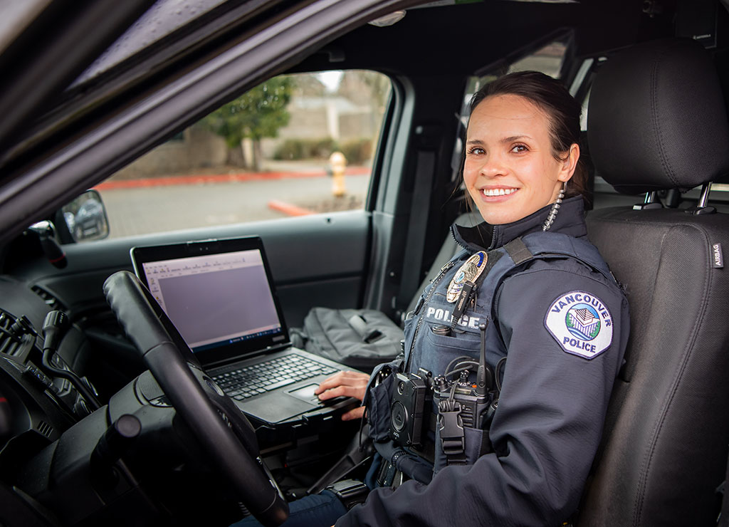 Female police officer working on laptop in cruiser