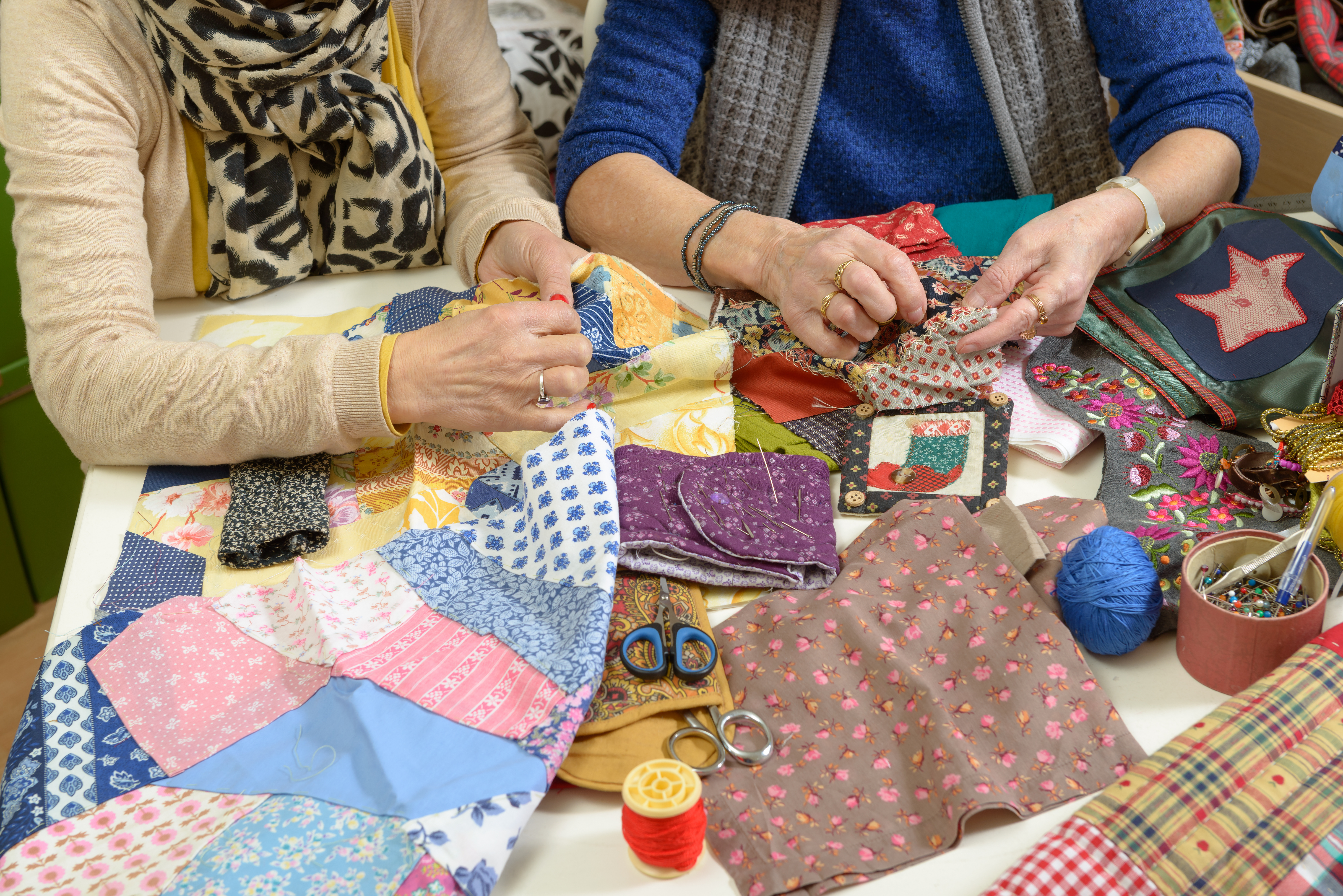 Overhead view of two people working on quilt projects together.