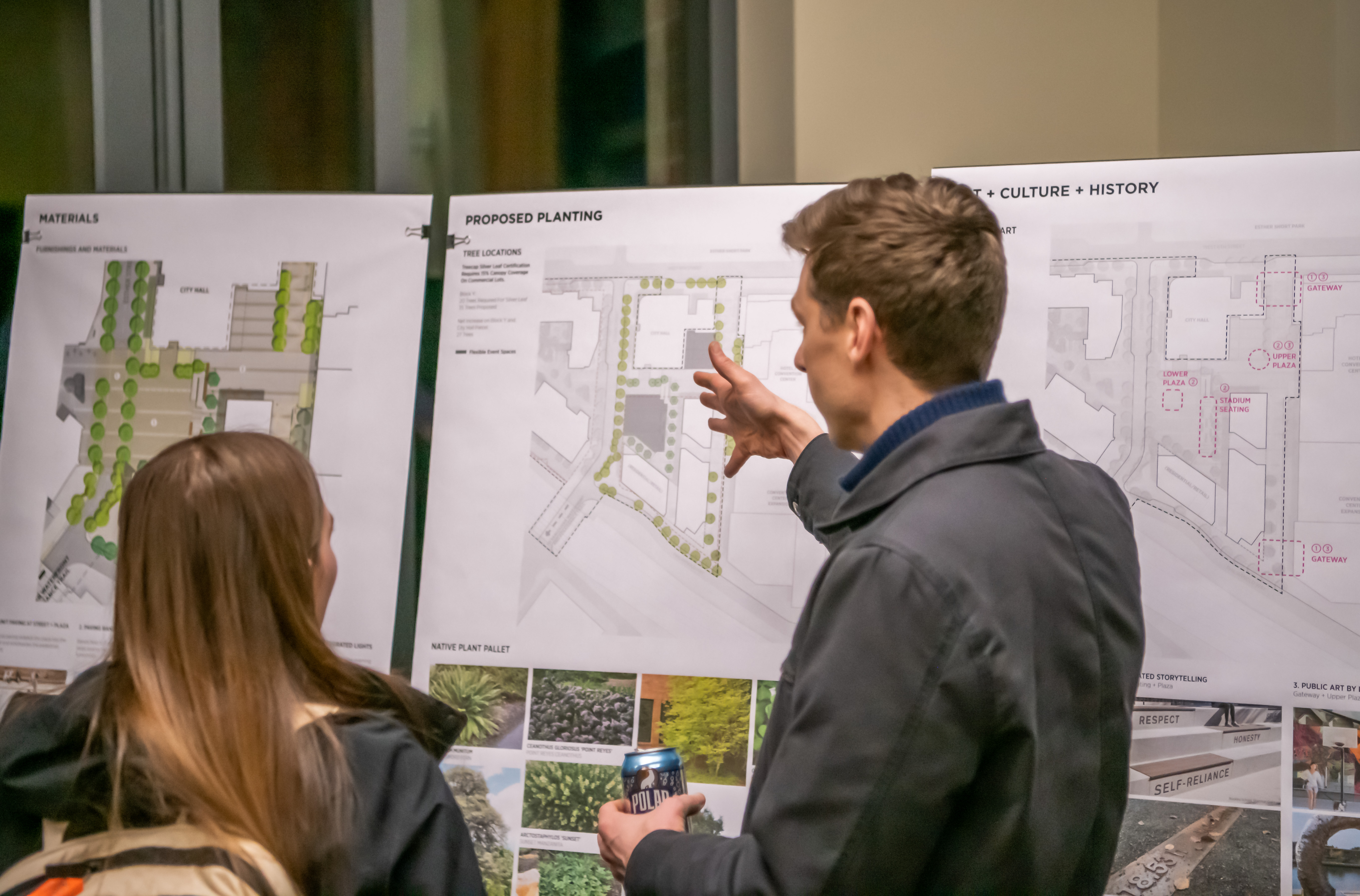 Two people looking at design boards for a public plaza at a community open house.