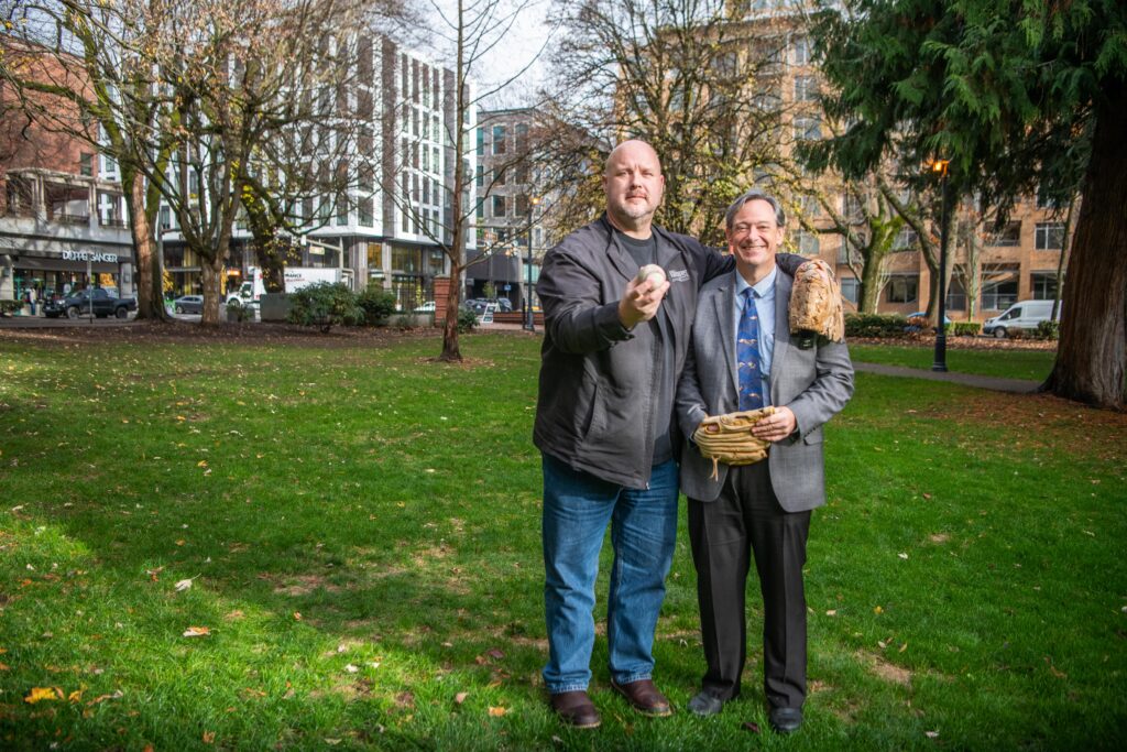 John Scukanec and Lon Pluckhahn pose for a photo with baseball and gloves following a game of catch at Esther Short Park