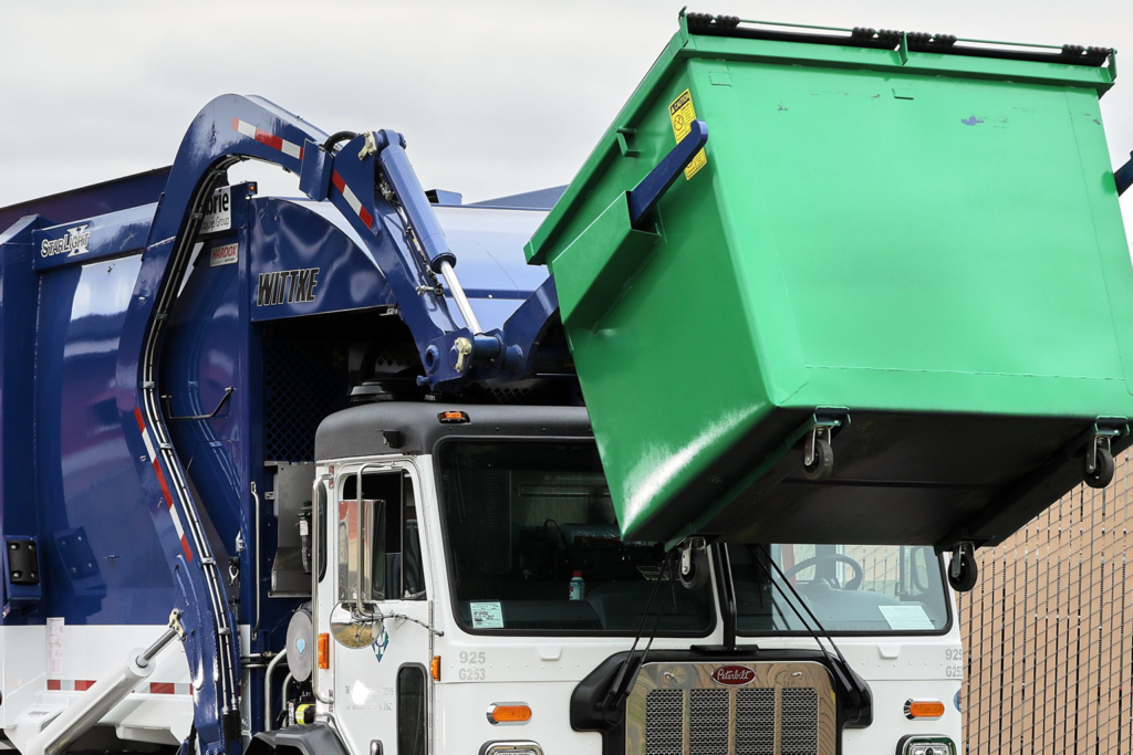 Waste Connections truck lifts a green commercial cart