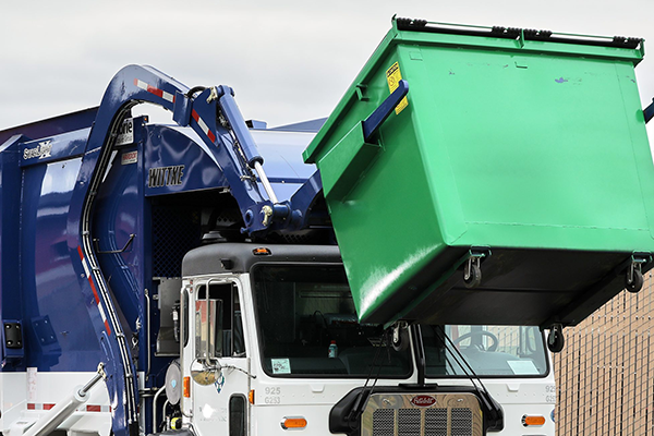 Waste Connections truck lifts a green commercial cart