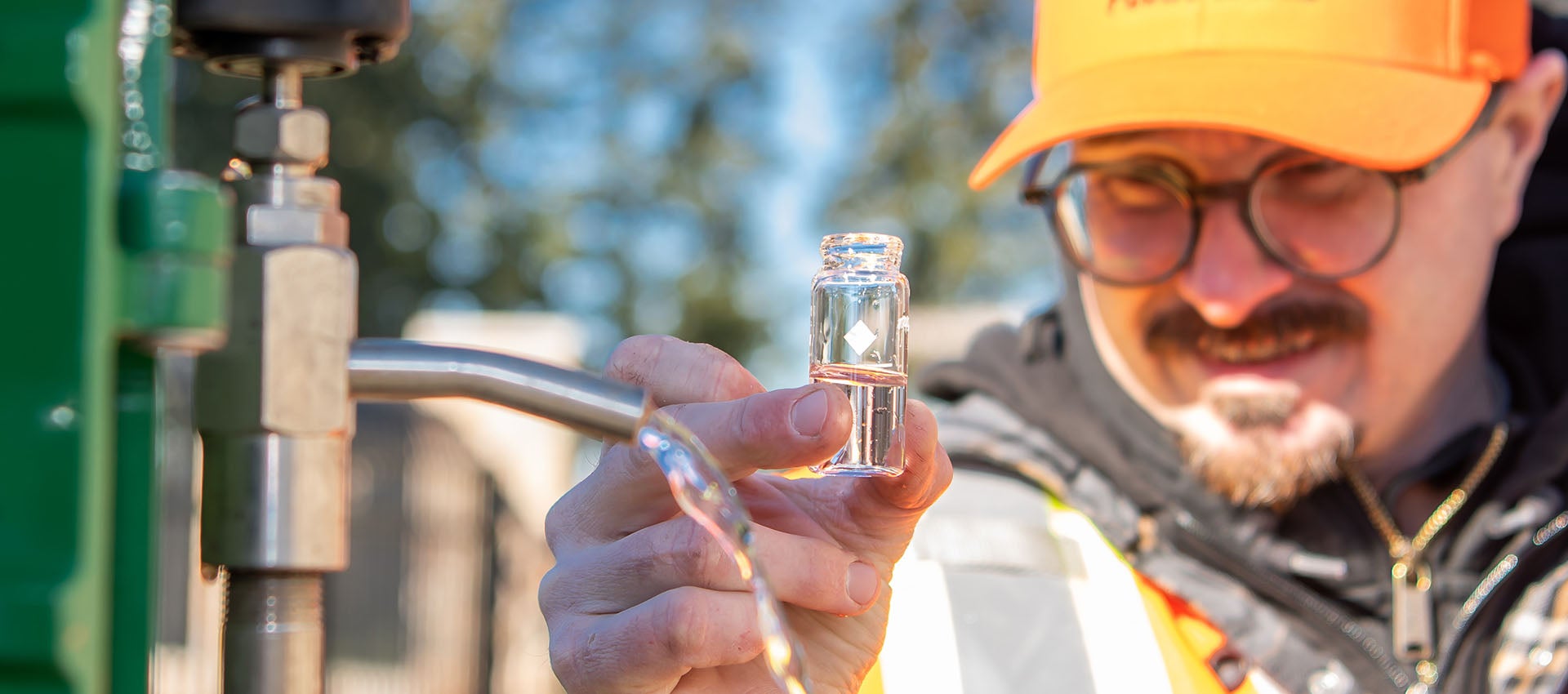 Public Works employee holding vial to test water sample from faucet